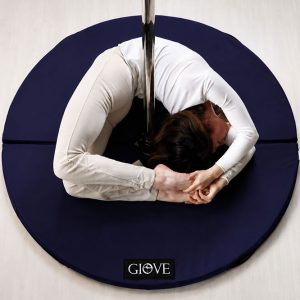 Atleta esegue una figura di flessibilità su palo da pole dance protetta dal Crash Mat Giove blu.